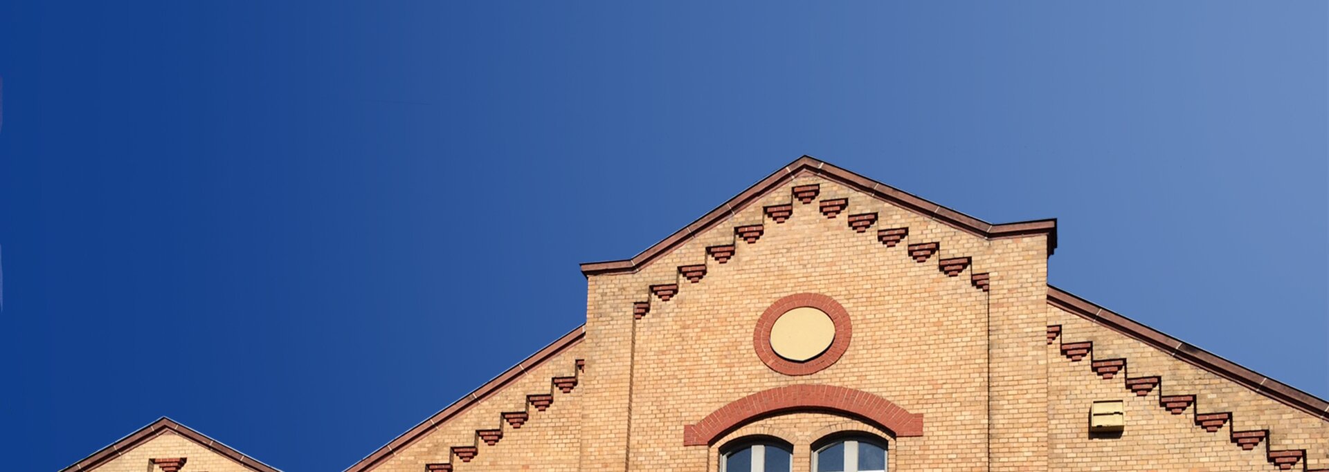 Titelbild e-werk | © e-werk Bad Homburg Ausschnitt Hausansicht e-werk Dachlinie mit blauem Himmel und Schriftzug e-werk Bad Homburg und webadresse | © e-werk Bad Homburg